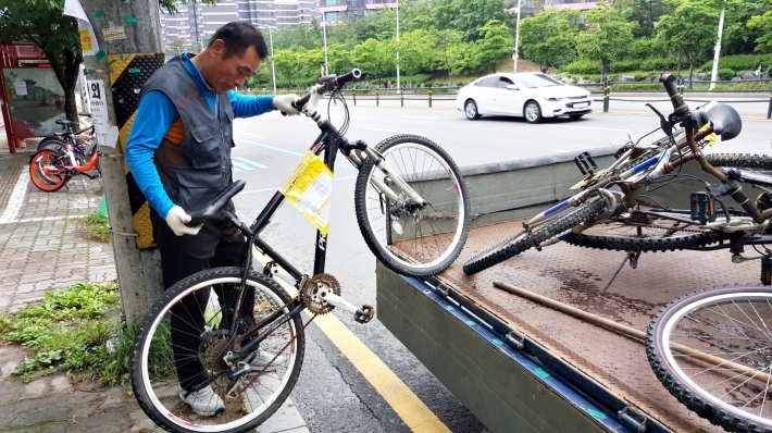  민간위탁업체 관계자가 무단방치 자전거를 수거하고 있다.   