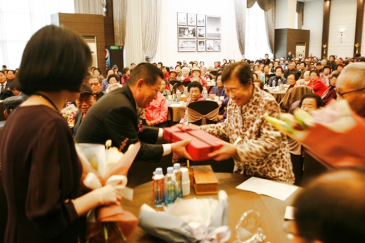 이정오 지동 주민자치위원장이 장수어르신에게 기념품을 전달하고 있다