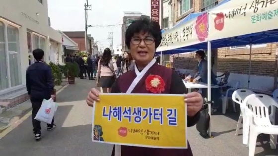 최수아 여성단체연합회장이 시민들의 염언을 담은나혜석 생가터 길 프랑카드를 들고 있다