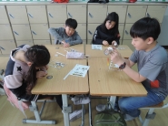 4학년 네 명의 학생들이 모둠책상으로 모여 앉아 고무동력기를 만들고 있다. 