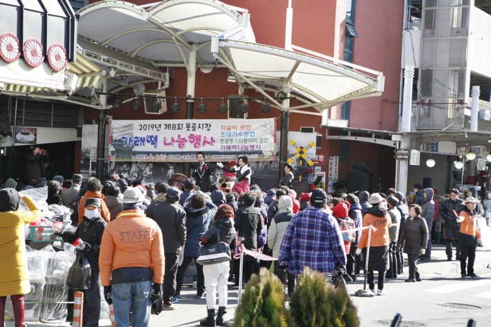 못골종합시장 가래떡 나눔 행사에 참여한 시민들이 무대 앞에 모여있다