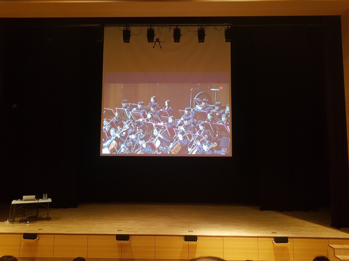 클래식아카데미가 SK아트리움 소공연장에서 열렸다. 강의전 최희준 지휘자가 연주하는 영상을 보여주고 있다.