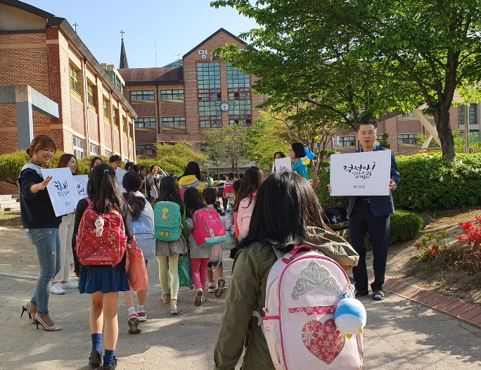 어린이날 축하 글귀가 적힌 피켓을 든 학부모님과 선생님들께서 등교하는 학생들을 맞이하고 있다.