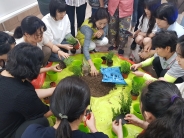 조경가드너 실습 장면, 작은 화분에 화초를 심고 있다.