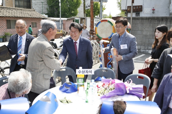 민효근 행궁동장과 한창석 주민자치회장이 장수어르신께 기념품을 증정하고 있다