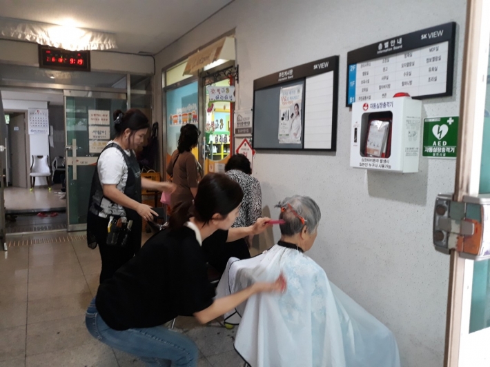 머털봉사단 회원들이 노인의 머리를 손질하고 있다. 