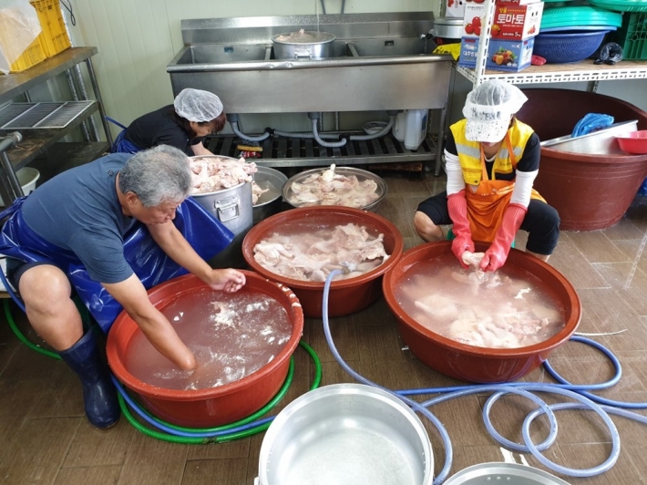 삼계탕을 끓일 닭을 손질하는 자원봉사자들