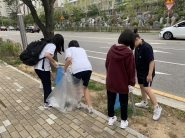 청소년자원봉사단들이 가로변 화단에서 생활폐기물을 수거하고 있다.