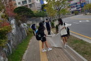 청소년 자원봉사단이 쓰레기를 봉투에 주워 담고 있다.