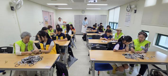 수원중촌초와 가온초 봉사단원들과 복지관 이음새봉사단원들이 함께 양말목으로 도어벨을 만들고 있다.