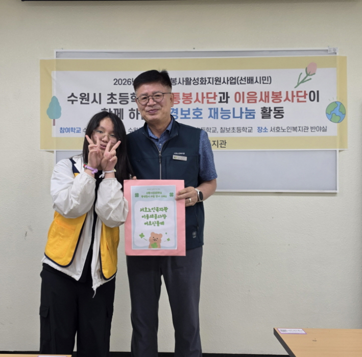 가온초 봉사단원이 노인복지관 관장님께 롤링페이퍼를 전달하고 사진을 촬영하고 있다.