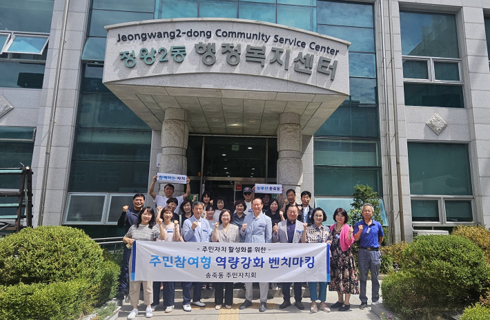 송죽동 주민자치회가 벤치마킹 후 정왕2동 행정복지센터 앞에서 기념촬영을 하고 있다.
