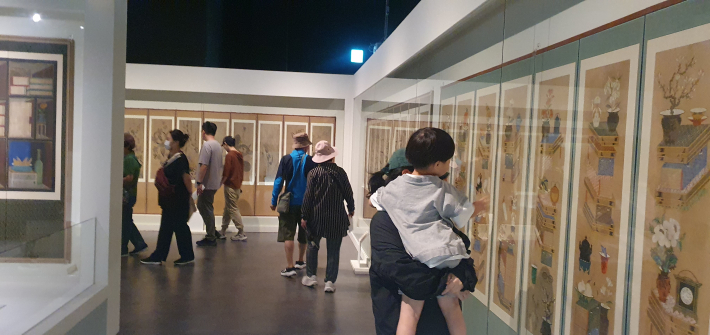 관람객들이 꽃을 소재로 한 회화 작품을 살펴보고 있다. 꽃과 새, 곤충이 어우러진 그림에는 행복과 풍요를 바랐던 옛사람들의 마음이 담겼다.