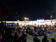 무대에서 수원시립예술단의 공연이 열리고 잔디밭에 앉은 시민들이 이를 관람하고 있다