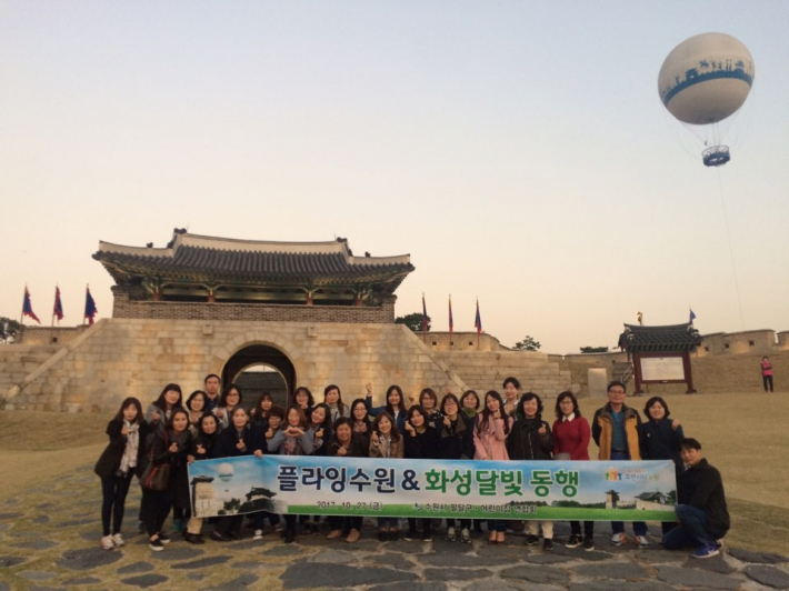 플라잉수원이 보이는 창룡문 앞에서 팔달구 어린이집 연합회 회원들이 서있음