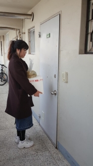 삼성전자와 함께하는 봄김치 전달, 전달 봉사자가 현관문 앞에서 김치 박스를 들고 있다.