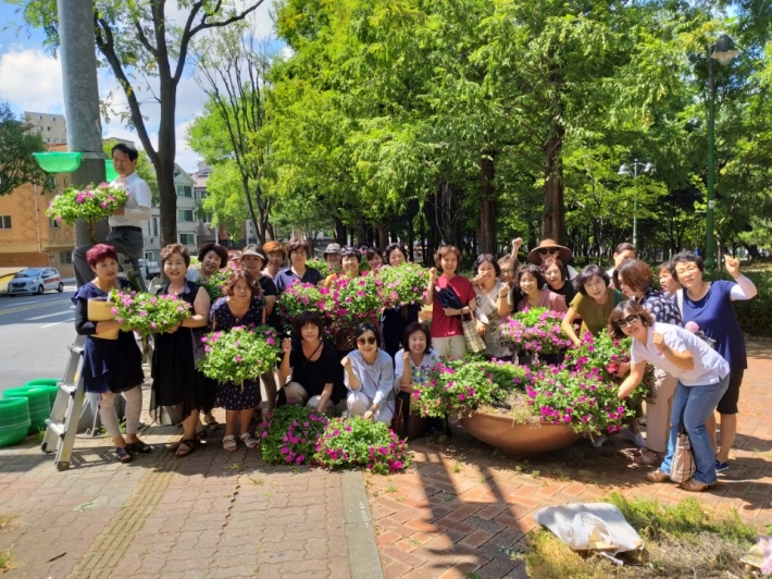 영통3동 주민들이 반달공원 인근 가로등주 꽃바구니 교체 작업에 쓰이는 아름다운 꽃바구니를 들고 있다.