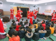 산타복장을 한 소리샘봉사단이 인형극을 공연하고 어린이들에게 선물을 주고 있다.