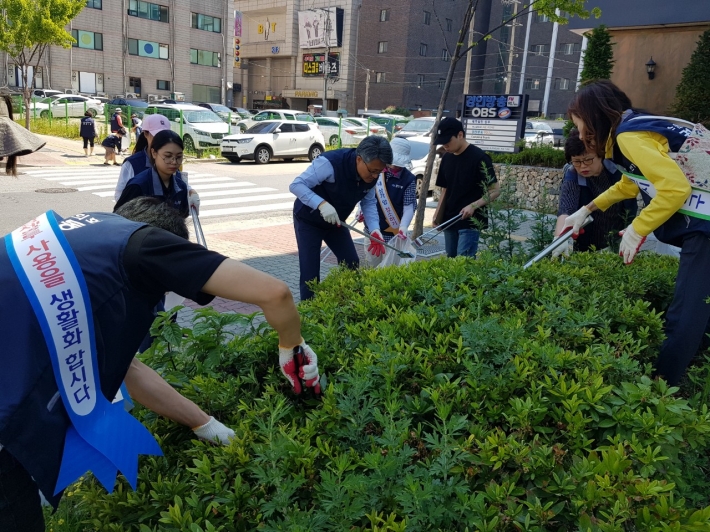 권선1동 관내 화단에 버려진 쓰레기들을 수거하고 있다.