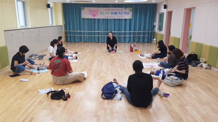 엄마들이 원형으로 둘러앉아 아기들을 앞에 눕히고 영유아 마사지를 하고 있다.