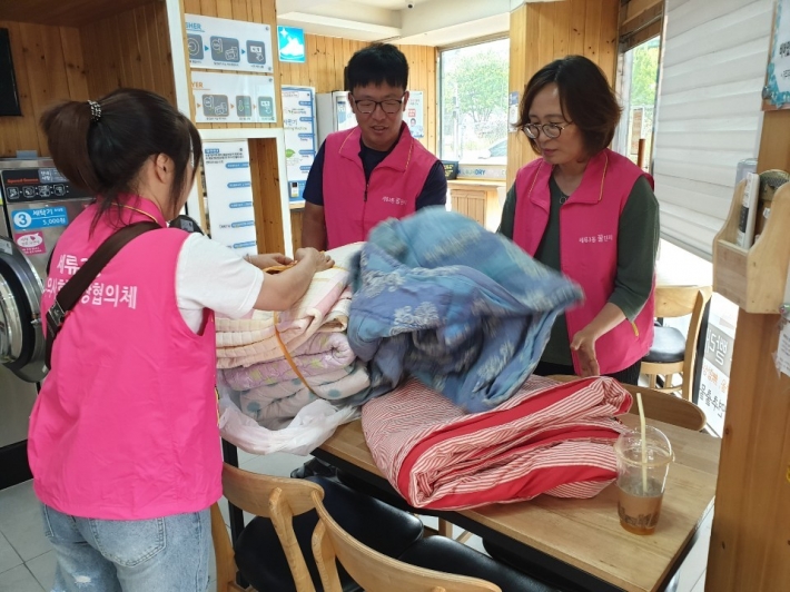세탁 건조후 뽀송뽀송해진 이불을 포장하고 있는 세류3동 지역사회보장협의체 위원들