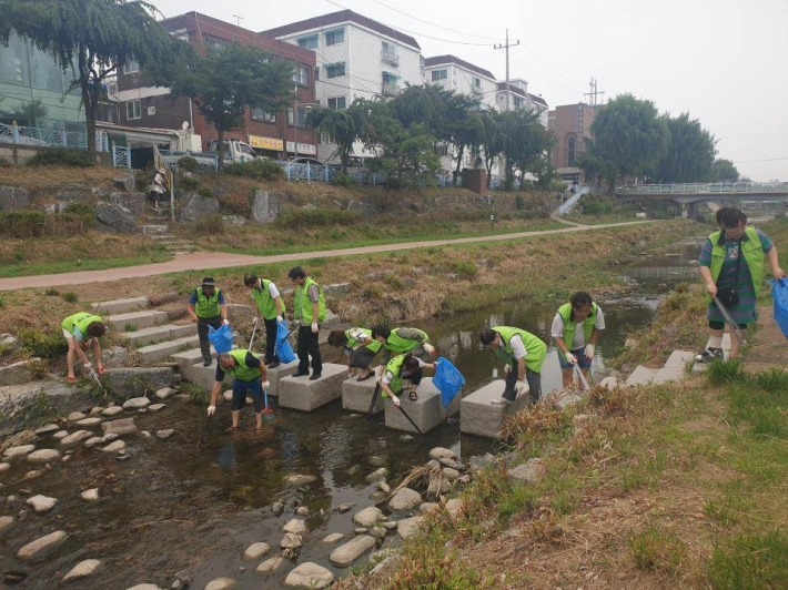 단체원들과 주민들이 함께 수원천에 있는 쓰레기를 수거하고 있다.