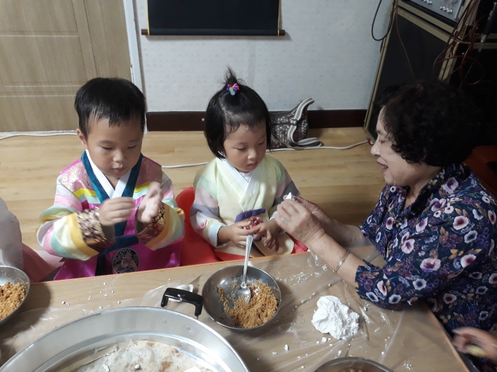 어린이들이 할머니에게 송편 만드는 방법을 배우고 있다. 