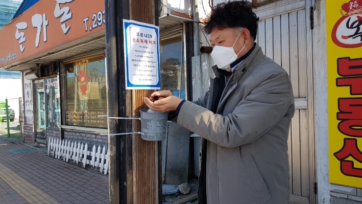 한 주민이 평동 버스정류장에 마련한 손소독제를 손에 바르고 있다. 