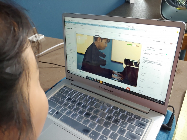 한 아이가 공연을 온라인 생중계로 관람하고 있다.  
