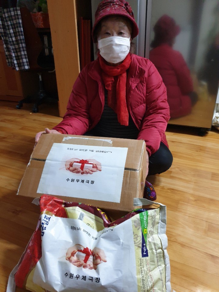 SK청솔노인복지관 최아무개 어르신이 수원우체국에서 준비한 후원물품을 전달받고 있다.