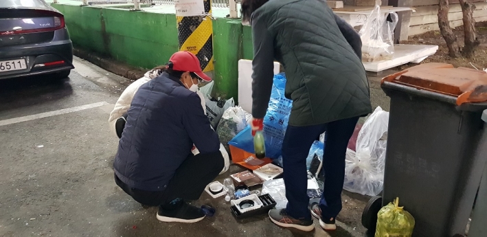 공직자와 관할 통장이 함께 무단투기된 쓰레기를 확인하고 있다.