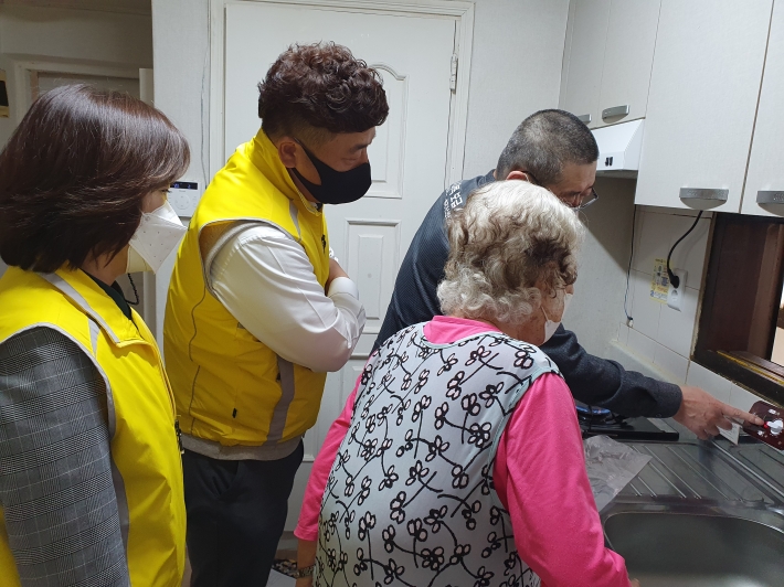 홀몸노인이 안전지킴이와 함께 가스타이머콕 설치를 지켜보고 있다. 