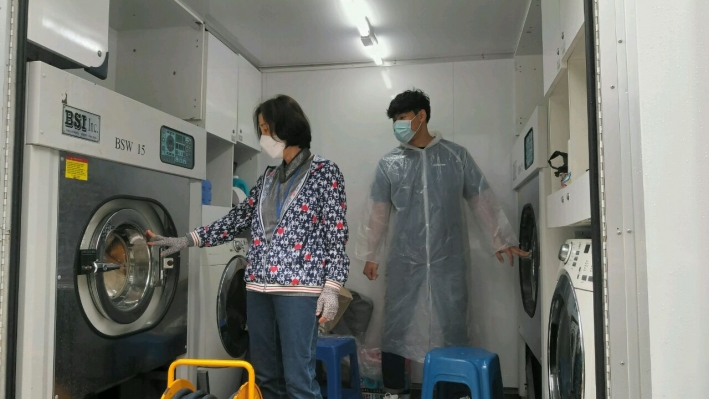 이동세탁차량에서 겨울이불 세탁상황을 점검하고 있는 동 지역사회보장협의체 위원과 봉사요원