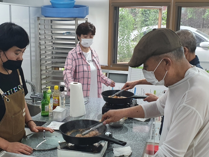 행궁동 지역사회보장협의체 요리조리봉사대원이 참여한 중장년에게 요리를 가르치고 있다.