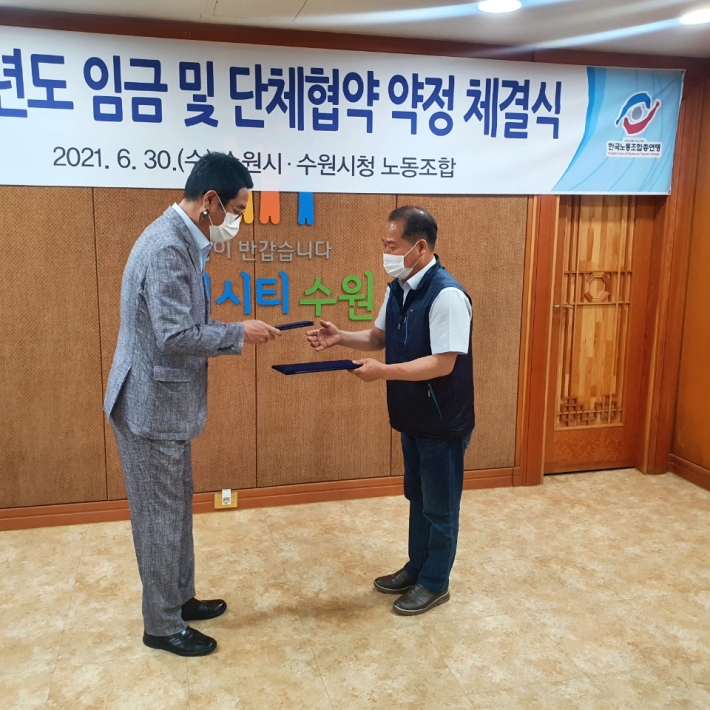 김기배 환경국장(왼쪽)이 김성복 노동조합위원장과 협약서를 교환하고 있다. 