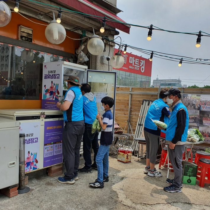 이성훈 서호천의 친구들 대표와 회원들이 공유냉장고에 나눔을 실천하고 있다.
