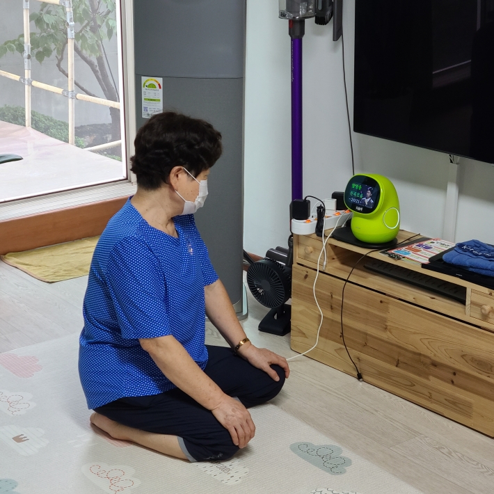 연무동에 거주하는 한 노인이 거실에 설치한 'AI 케어로봇 시니어'를 살펴보고 있다.