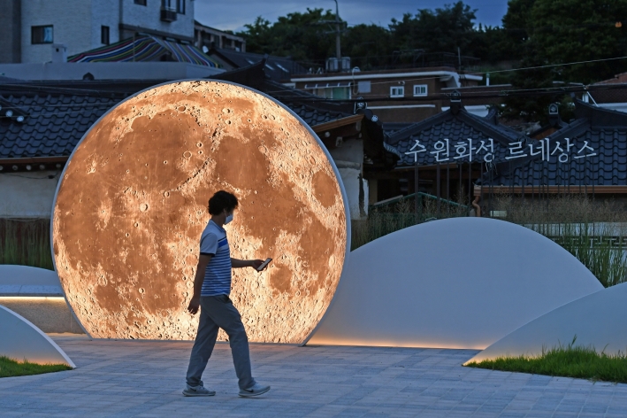 행궁동 도시재생사업의 일환으로 남수동 길가에 조성된 경관조명 '팔달산에 뜨는 달' 앞으로 한 시민이 지나가고 있다.