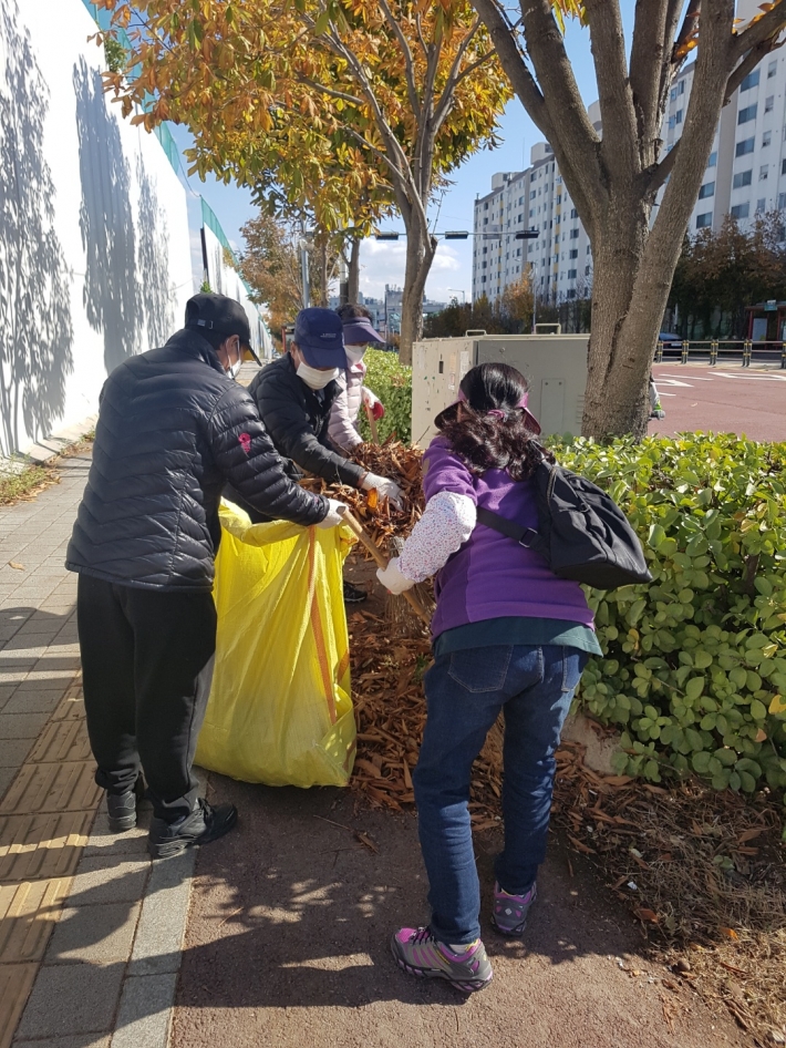 환경관리원과 단체원들이 낙엽을 치우고 있다.