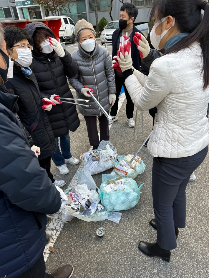 통장 및 주민들이 쓰레기봉투를 직접 파봉하여 내용물을 확인하고 있다.
