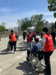 자원봉사자와 장애인이 광교호수공원을 산책하고 있다