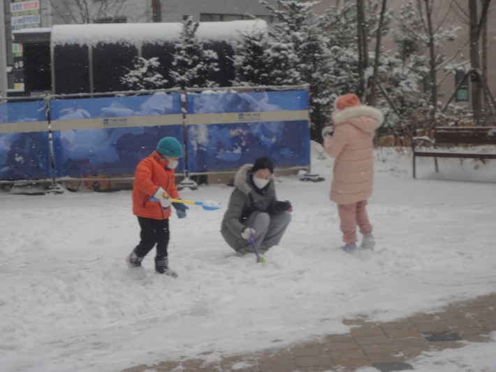 눈이내린 아파트단지에 어린이들과 엄마가 눈장난을하고있다.