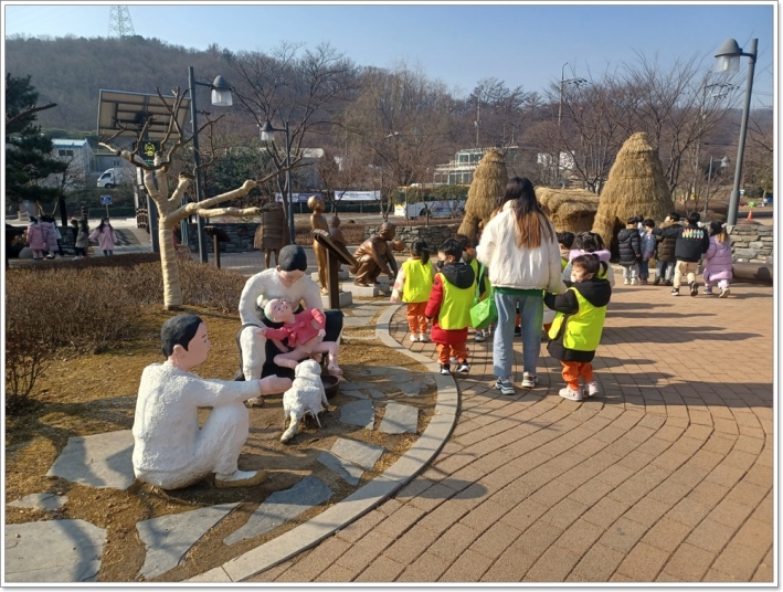 화장실 문화공원에서는 노란 옷을 입은 유치원생들이 원뿔형 볏짚 화장실을 보며 신기해 하고 있다.