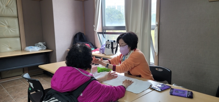 동남보건대학교 뷰티케어학과 교수가 참여 어르신께 손마사지를 진행하며 대화를 나누고 있다.