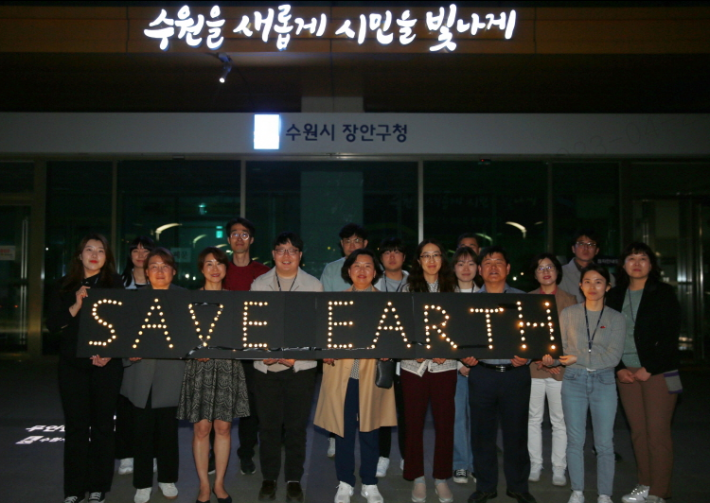 장안구 공직자들이 구청 광장 앞에서 손팻말을 들고 지구살리기 퍼포먼스를 하고 있다.