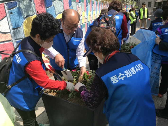 최덕헌 새마을금고 이사장과 대의원들이 매탄1동 관내에서 함께 봄 꽃을 식재하고 있다
