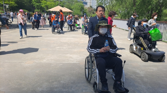 장애인이 휠체어로 호수 한 바퀴를 완주하고 있다. 