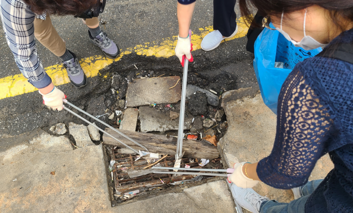조원1동 주민들이 쓰레기로 막힌 빗물받이를 청소하고있다.