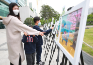 만석거 벚꽃축제 어린이 그림대회에서 입상한 어린이와 가족이 전시 작품을 둘러보고 있다. 