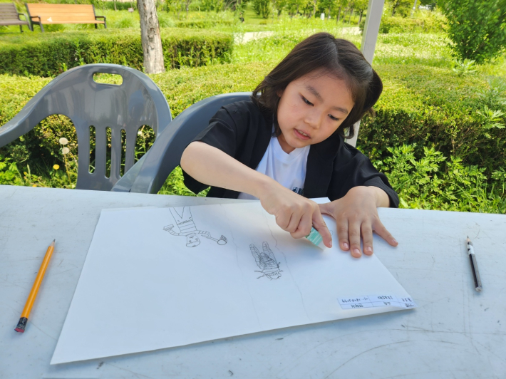 어린이 그림대회에 참가한 어린이가 집중하여 그림을 그리고 있다